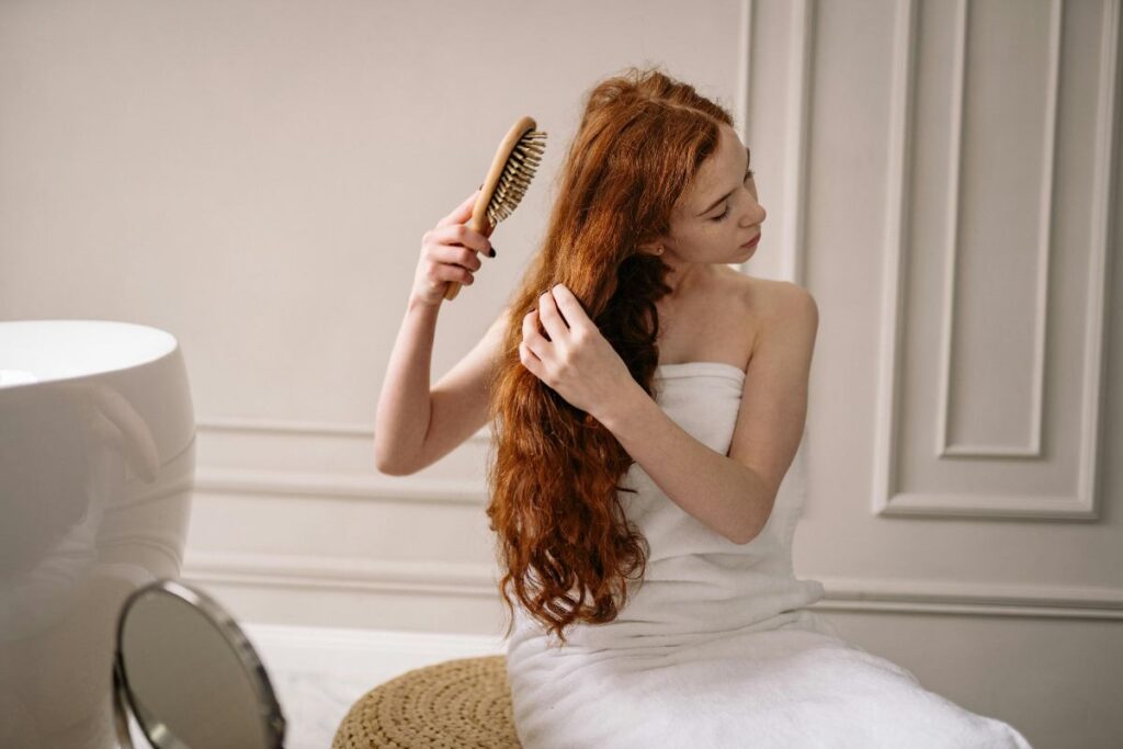 donna che si pettina i capelli lunghi e rossi