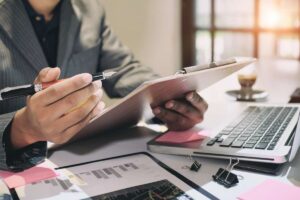 mani di persona con penna, pc e fogli