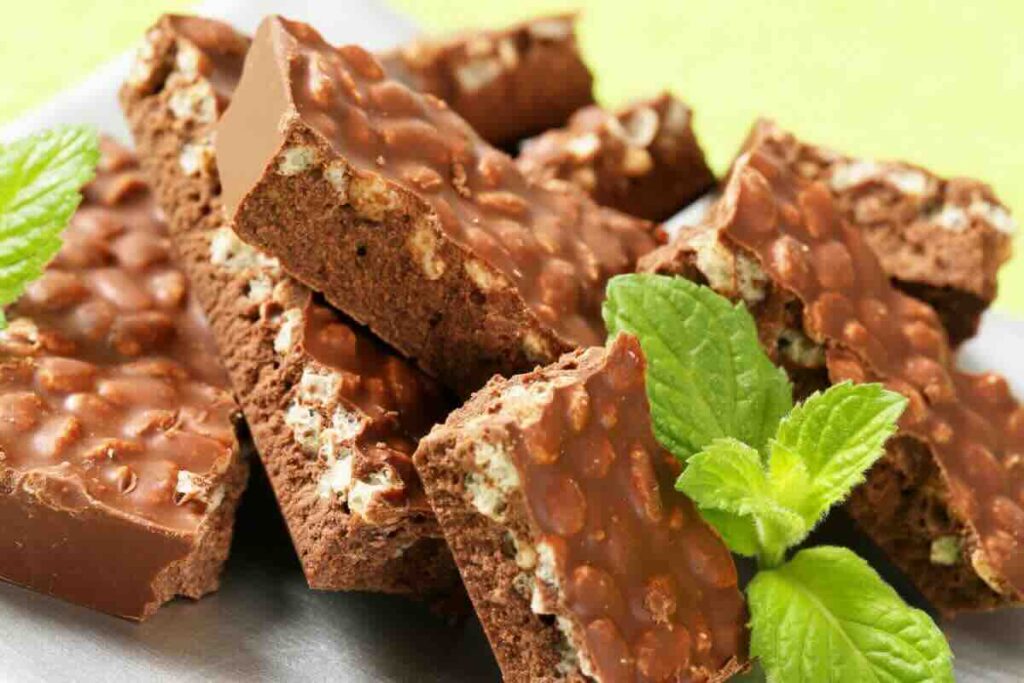 Pezzi di barrette di cioccolato con cereali e foglie di menta